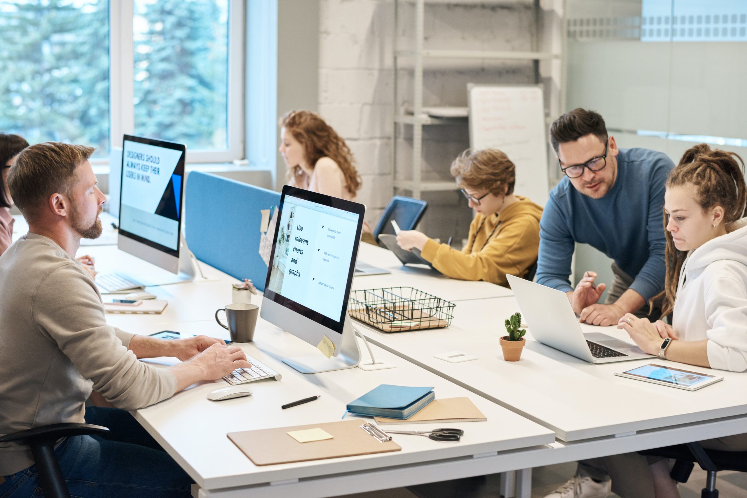Photo depicting staff seated at a large table with computers